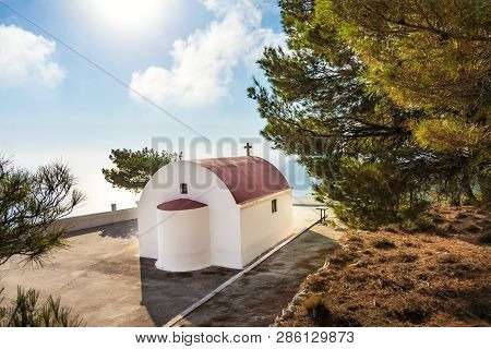 View Of Greek Orthodox Church With Cyclamen Roof Next To Forest, Sea In Background (rhodes, Greece)