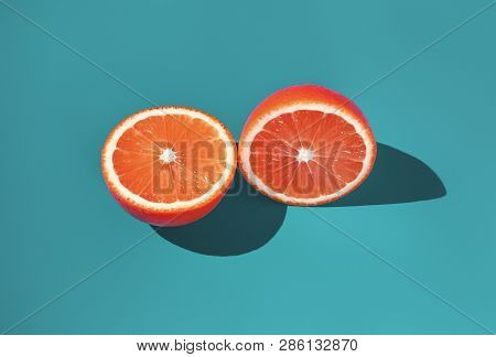 Two Halves Of Ripe Orange On A Green Background In Bright Sunlight