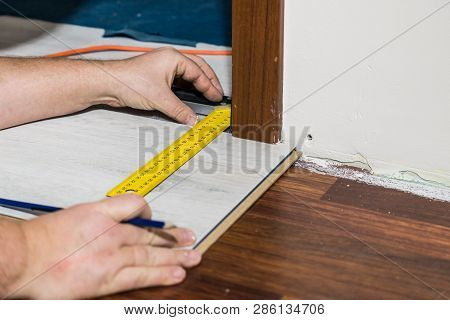 Construcion Worker Measuring Floor Panels Using Ruler And Pencil. Home Renovation Concept.