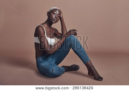 Gorgeous Sensual Model. Attractive Young African Woman Looking At Camera While Sitting Against Brown