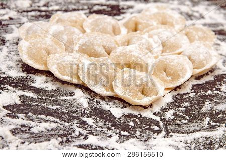 Raw Yellow Dumplings, Flouted Lie In The Shape Of A Heart On A Wooden Brown Board
