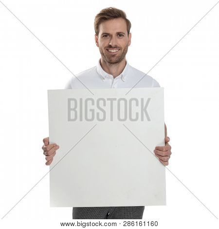 smiling casual man holding blank board on white background