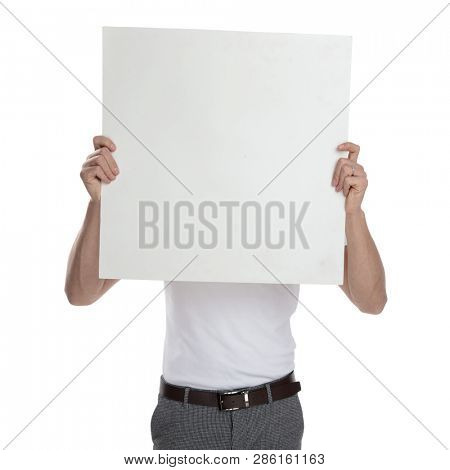 young casual man covering face with blank billboard on white background