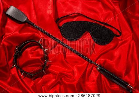 Bondage, Kinky Adult Sex Games, Kink And Bdsm Lifestyle Concept With A Whip, Collar, Eye Mask On Red