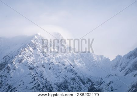 Some Clouds Around Snow Covered Mountain Peak Grimming On A Sunny Winter Day In Styria, Austria