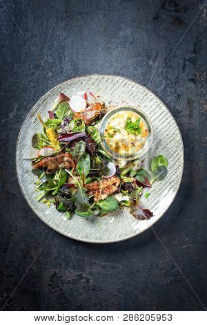 Backed Norwegian skrei cod fish filet with fresh lettuce, mushroom and parmesan as top view on a modern design plate 