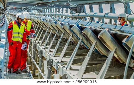 Conveyor Belt Transporting Platinum Ore For Processing With Mining Safety Inspectors Checking For Da