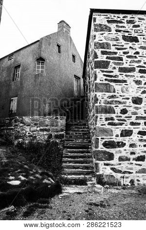 Stairway Through Old Stone Buildings In Black And White