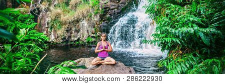 Wellness yoga woman practicing meditation in nature by watefall and lush forest. Banner panorama of health and fitness, mindfulness concept.