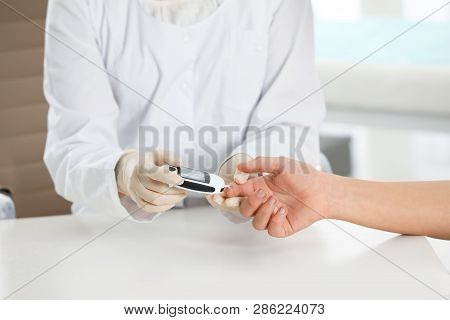 Doctor Checking Patient's Blood Sugar Level With Digital Glucometer At Table, Closeup. Diabetes Cont