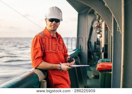 Deck Officer On Deck Of Offshore Vessel Holds Vhf Walkie-talkie Radio