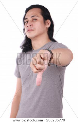 Portrait Of Good Looking Long Haired Young Asian Man Shows Thumbs Down Gesture With His Finger Isola