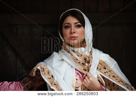 Young Azeri Woman In Traditional Azerbaijani Dress Standing At The Wooden Door