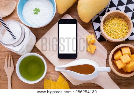 Wood Table With Blank Screen On Smart Phone, Tablet, Cell Phone  With Breakfast.