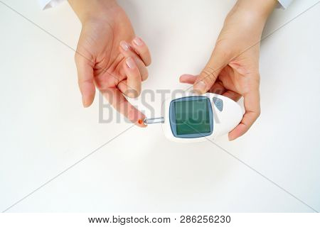 Photo of woman's hand with glucometer.
