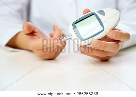Picture of woman's hand with glucometer.