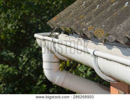 Roof Gutter. House Asbestos Roof With Plastic Roof Gutter Pipe. House Guttering With Holders And Old