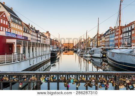 A  Bridge Over The Nyhavn Canal Full Of Lovers Locks Fixed To The Railing In Morning Twilight, Copen