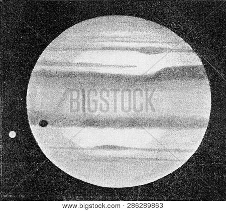 Jupiter with one of his five moons whose shadow is visible on the planet, vintage engraved illustration. From the Universe and Humanity, 1910.