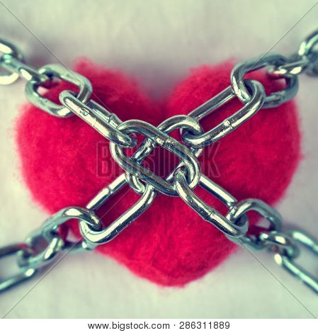 Red Wool Heart Locked With Metal Chain On White Bed Sheet