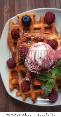 Plate of belgian waffles with ice cream  and fresh berries - raspberries and blueberries.