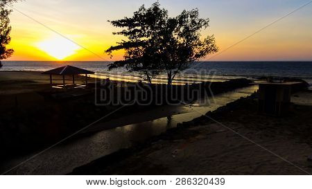 Beautiful Golden Sunset Sandy Beach And Tropical Trees At Taman Damai Or Surrender Point Landmark Ww