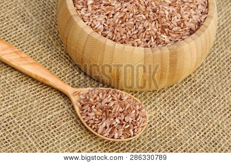 Uzbek Devzira, The Red Rice For Pilaf In A Bamboo Bowl And A Wooden Spoon