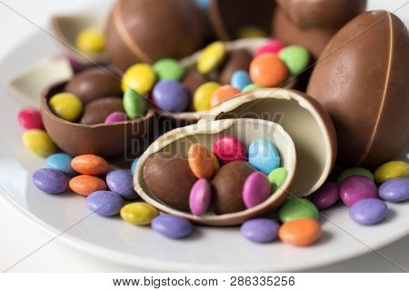 easter, sweets and confectionery concept - close up of chocolate eggs and candy drops on plate