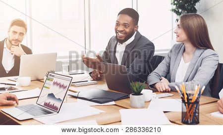 Young Managers Analysing Graphs And Charts On Laptops At Meeting