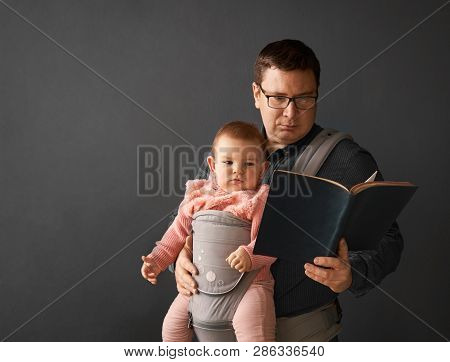Fathre And His Kid In Baby Carrier At The Grey Background Wall, Baby Wearing Concept