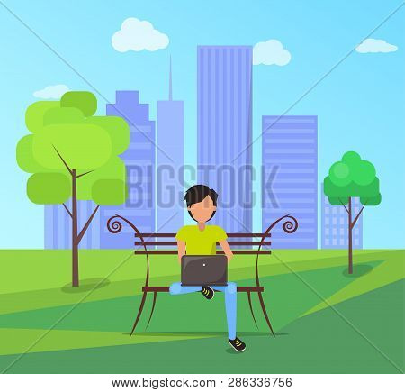 Man Sitting On Bench In City Park On Background Of Skyskrapers With Modern Laptop In Free Wi-fi Zone