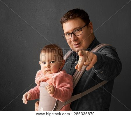 Fathre And His Kid In Baby Carrier At The Grey Background Wall, Baby Wearing Concept