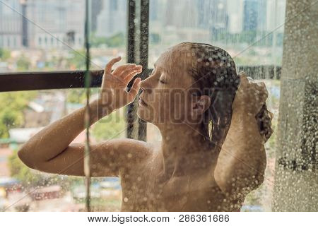 Beautiful Woman In The Shower Behind Glass With Drops On The Background Of A Window With A Panoramic