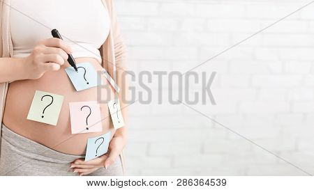 Concept Of Choosing Baby Name. Pregnant Woman With Question Marks On Paper Stickers On Tummy, Panora