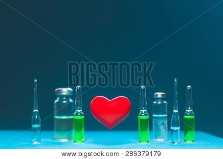 Concept Of A Healthy Heart. Red Volumetric Heart On The Background Of Ampoules With Medicines