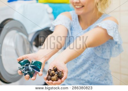 Woman Comparing Washing Laundry Nuts And Chemicals Detergent Blue Pods. Alternative Household Duties