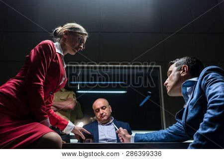 Low-angle view of a female attorney in disagreement with the prosecutor, during the preliminary hearing of an unwilling suspect in the office of a police station