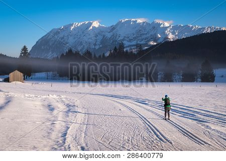 Woman Running Cross-country Skiing In Bad Mitterndorf With Nice View To Mountain Grimming On A Sunny