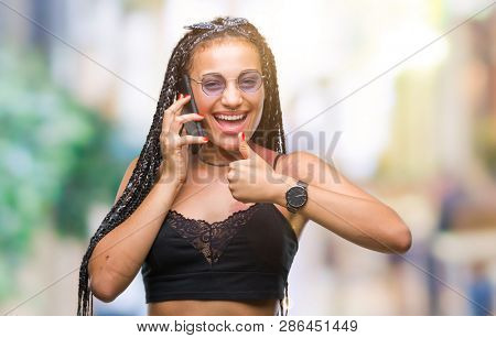 Young braided hair african american with birth mark talking on smartphone over isolated background happy with big smile doing ok sign, thumb up with fingers, excellent sign