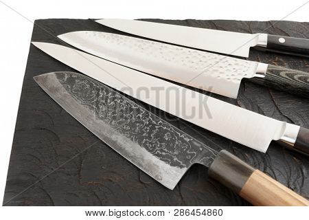 Four different knives on black wooden cutting board