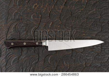 Small utility knife on dark wooden surface