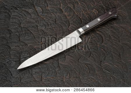 Stainless steel knife on black wooden cutting board