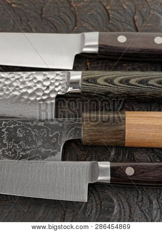 Knife handles and blades on black cutting board, close-up, fragment