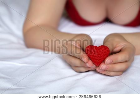 Sexy Woman With Red Knitted Heart In Hands, Declaration Of Love. Seductive Girl In Red Bra Lying On 