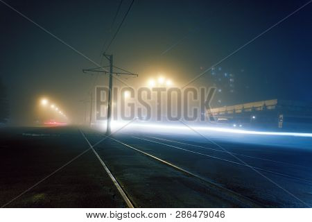 Road With Poles With High-voltage Wires And Tram Tracks Or Tram Rails , Evening Fog On The Streets, 