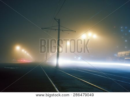 Road With Poles With High-voltage Wires And Tram Tracks Or Tram Rails , Evening Fog On The Streets, 