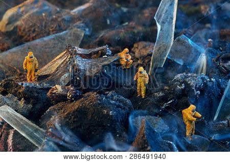 Conceptual photo of toy people in hazmat suits and wings of a dead dragonfly. Environmental disaster concept.