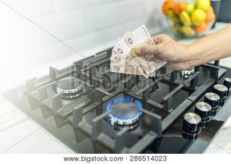 Cooktop With Burning Gas Ring With Hands Holding Money Uah Hryvnas For Combustion At Home.