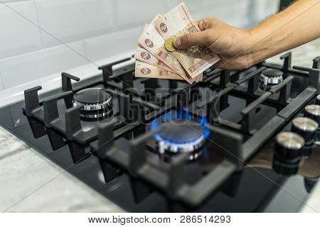 Cooktop With Burning Gas Ring With Hands Holding Money Uah Hryvnas For Combustion At Home.