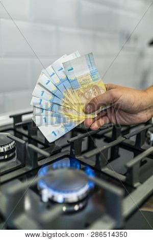 Cooktop With Burning Gas Ring With Hands Holding Money 9 Uah Hryvnas For Combustion At Home.